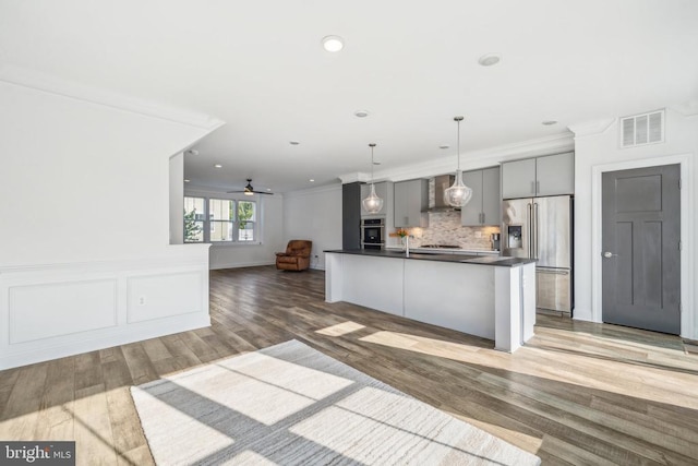 kitchen with wall chimney exhaust hood, gray cabinetry, tasteful backsplash, ornamental molding, and appliances with stainless steel finishes