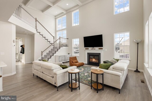 living room featuring beam ceiling, coffered ceiling, and light wood-type flooring