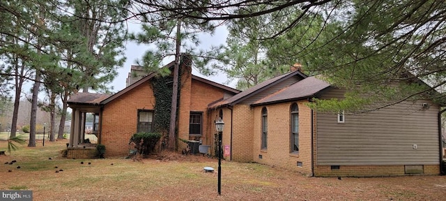 view of property exterior featuring crawl space, brick siding, roof with shingles, and a chimney