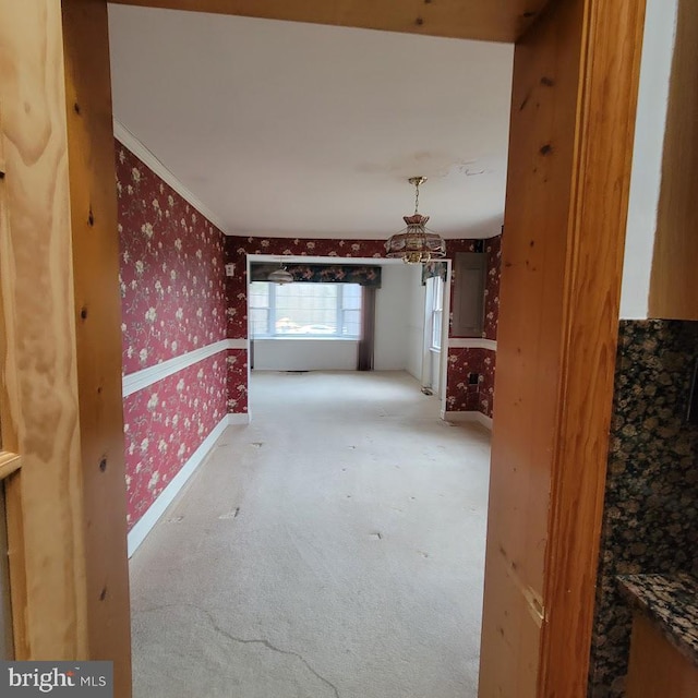 corridor featuring baseboards, wallpapered walls, ornamental molding, carpet flooring, and a notable chandelier