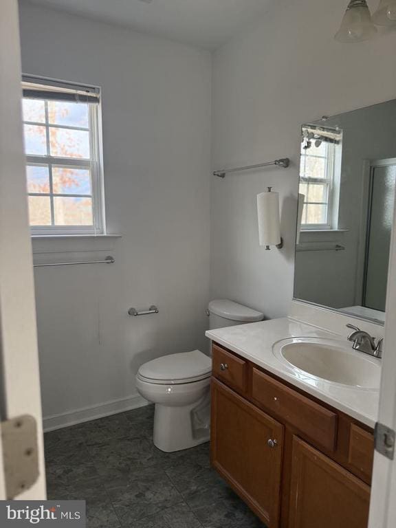 bathroom featuring vanity, a healthy amount of sunlight, an enclosed shower, and toilet