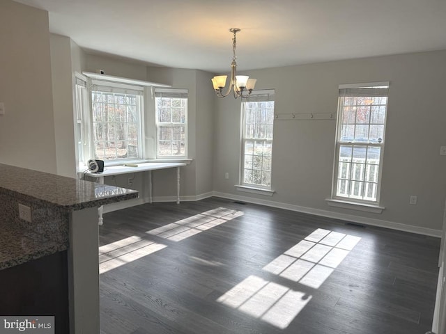 unfurnished dining area with a notable chandelier, plenty of natural light, and dark wood-style floors