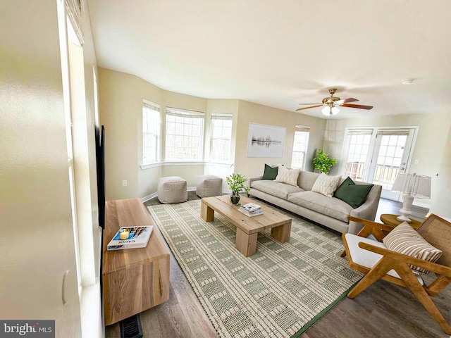 living room with a ceiling fan, baseboards, and wood finished floors