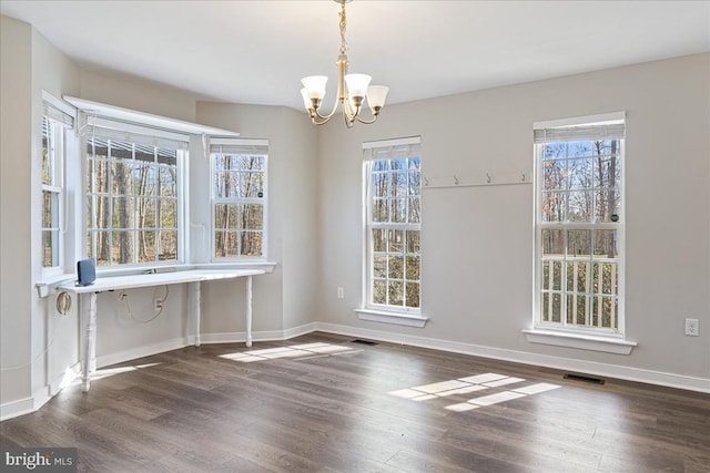 unfurnished dining area with a wealth of natural light, visible vents, baseboards, and wood finished floors