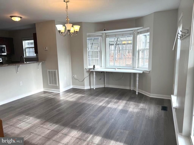 unfurnished dining area with dark wood-type flooring, sink, and an inviting chandelier