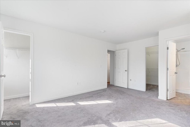 unfurnished bedroom with a walk in closet, carpet, and a closet