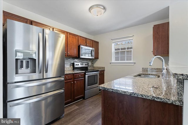 kitchen featuring tasteful backsplash, dark wood-type flooring, appliances with stainless steel finishes, stone countertops, and a sink