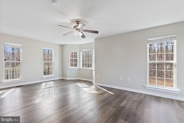 unfurnished room featuring visible vents, a ceiling fan, dark wood-type flooring, and baseboards