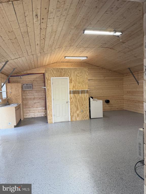 interior space with vaulted ceiling, wooden ceiling, and wood walls