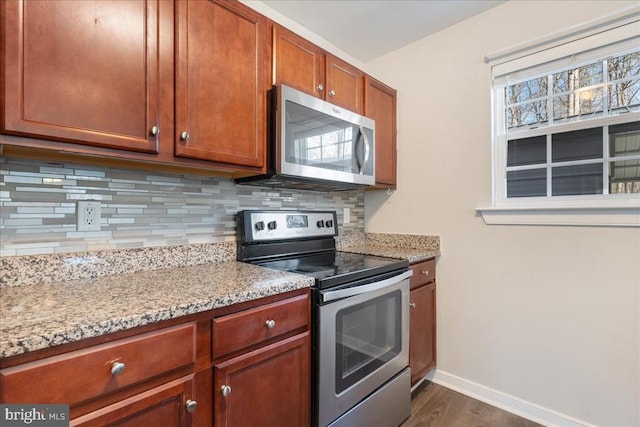 kitchen with light stone countertops, baseboards, dark wood-style flooring, appliances with stainless steel finishes, and backsplash