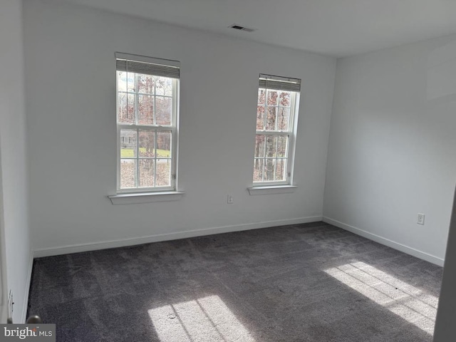 unfurnished room with plenty of natural light and dark colored carpet