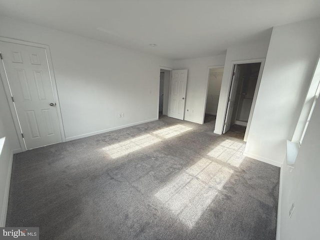 unfurnished bedroom featuring a walk in closet and light carpet