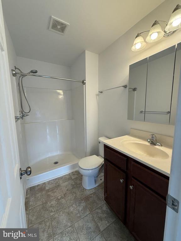 full bath featuring visible vents, toilet, walk in shower, and vanity