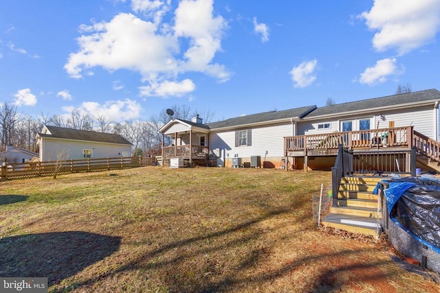 rear view of property featuring a wooden deck, cooling unit, and a lawn