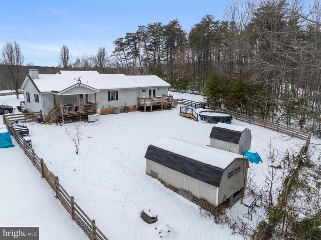 snow covered house featuring a shed and a deck