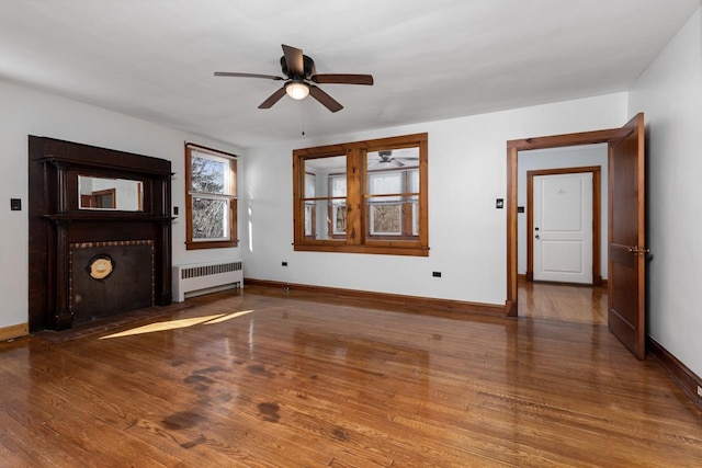 unfurnished living room featuring hardwood / wood-style floors, radiator heating unit, and ceiling fan