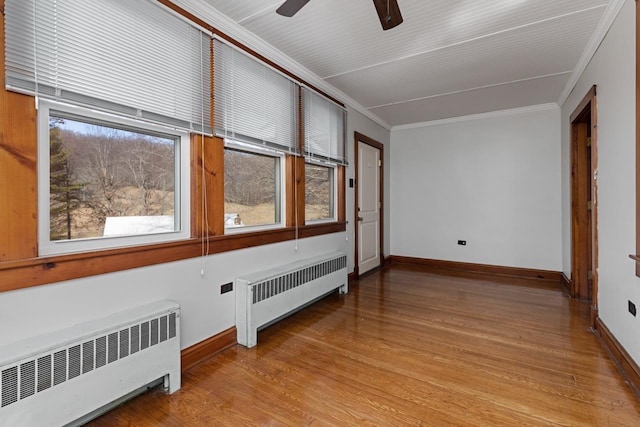 empty room with light hardwood / wood-style flooring, radiator heating unit, ornamental molding, and ceiling fan