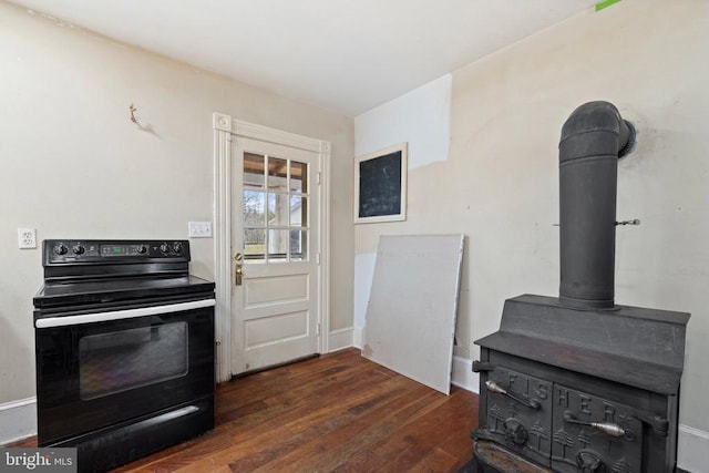 kitchen featuring black electric range oven, a wood stove, and dark hardwood / wood-style flooring