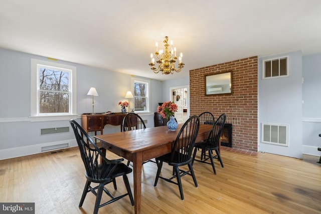 dining room with a notable chandelier, a fireplace, and light hardwood / wood-style floors