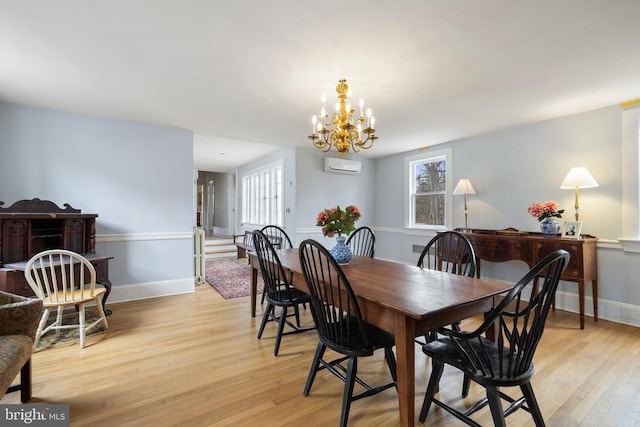 dining area featuring plenty of natural light, an AC wall unit, a chandelier, and light wood-type flooring