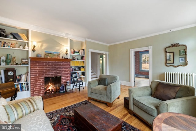 living room with crown molding, radiator, a fireplace, and light hardwood / wood-style floors