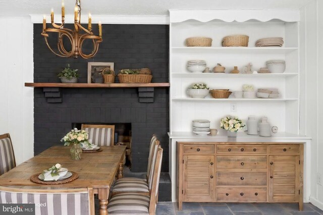 dining area with an inviting chandelier, a fireplace, and built in features