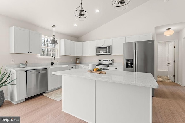 kitchen with decorative light fixtures, light wood-style flooring, appliances with stainless steel finishes, and a kitchen island