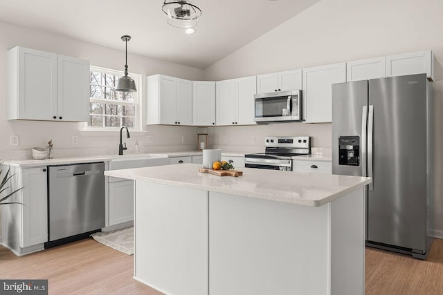 kitchen with light wood-type flooring, a sink, a center island, appliances with stainless steel finishes, and lofted ceiling