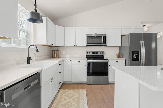 kitchen featuring appliances with stainless steel finishes, white cabinetry, lofted ceiling, and a sink