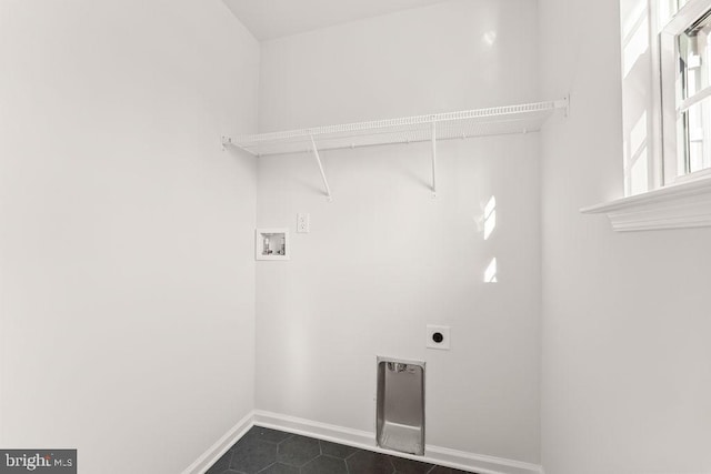 washroom featuring electric dryer hookup, washer hookup, dark tile patterned floors, baseboards, and laundry area