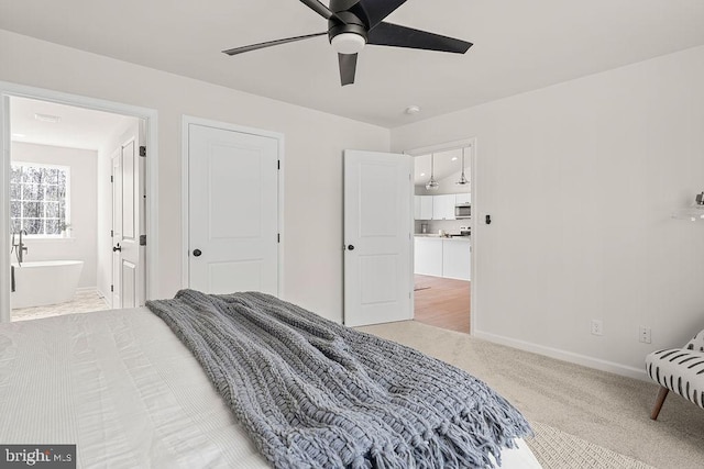 carpeted bedroom featuring ceiling fan, ensuite bathroom, and baseboards