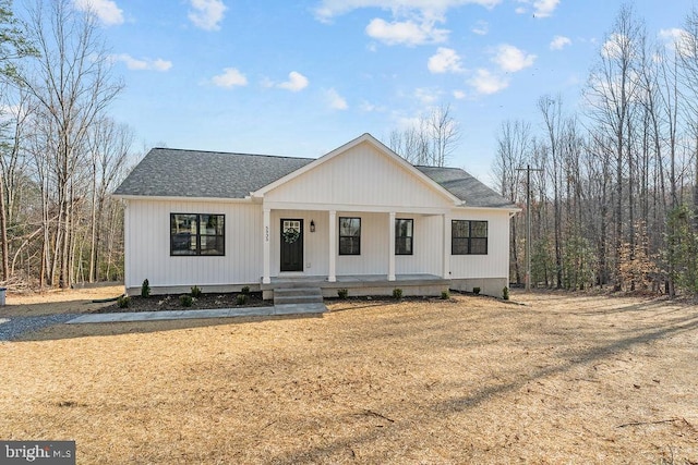 modern farmhouse featuring a porch, roof with shingles, and crawl space