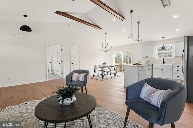 living room with baseboards, light wood finished floors, high vaulted ceiling, an inviting chandelier, and recessed lighting