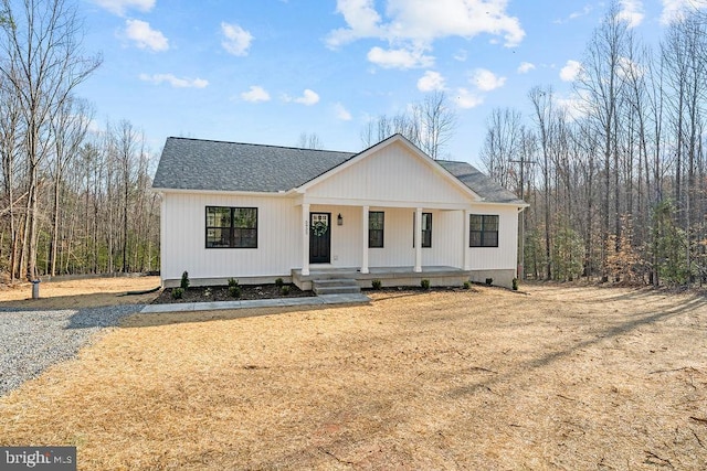 modern inspired farmhouse featuring covered porch and roof with shingles