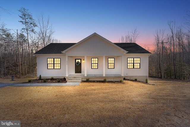 modern inspired farmhouse with a front lawn, a porch, and roof with shingles