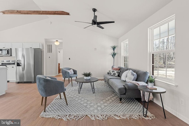 living area with light wood finished floors, visible vents, baseboards, beamed ceiling, and a ceiling fan