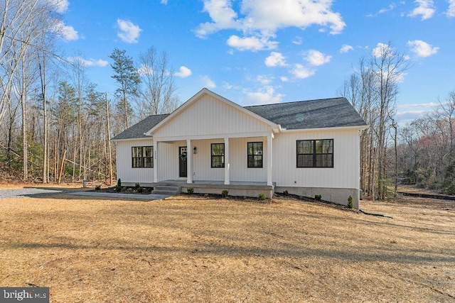 modern farmhouse featuring covered porch and a shingled roof