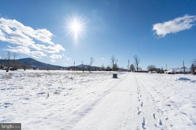 yard covered in snow featuring a mountain view