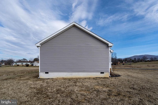 view of side of home featuring a lawn, crawl space, and a mountain view