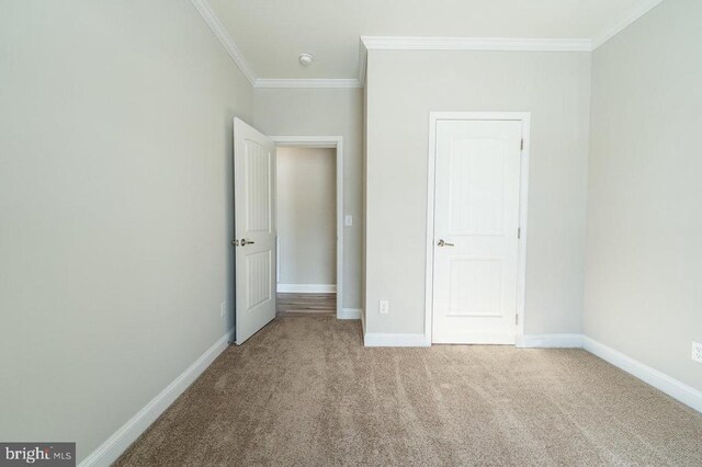 unfurnished bedroom with carpet floors, baseboards, and crown molding