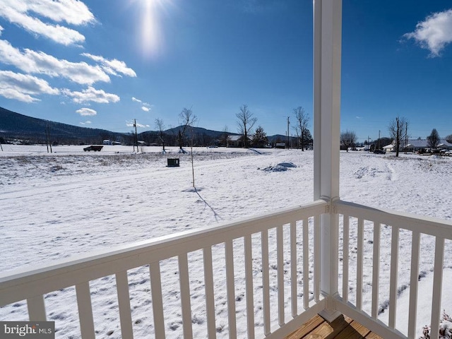 snow covered deck with a mountain view