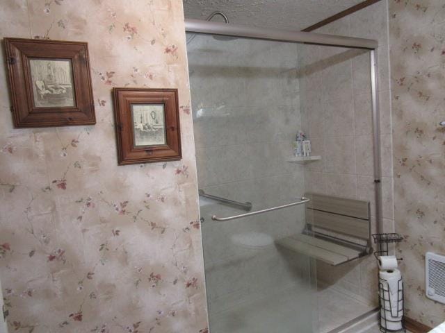 bathroom featuring a shower stall and wallpapered walls