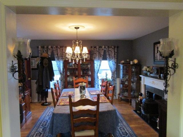 dining room featuring a notable chandelier, a fireplace, and wood finished floors