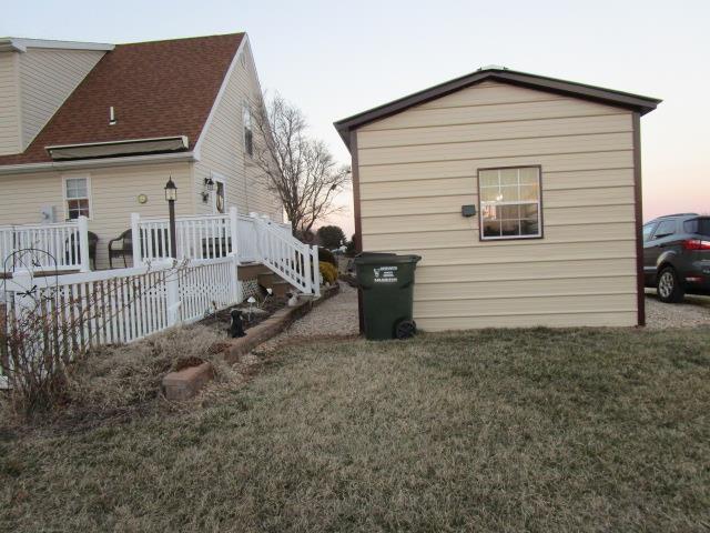 property exterior at dusk featuring a deck and a lawn