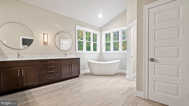 bathroom with vanity, lofted ceiling, hardwood / wood-style floors, and a bathtub