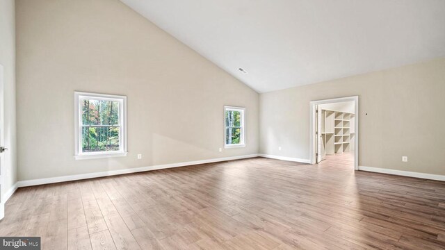 unfurnished room with high vaulted ceiling and light wood-type flooring