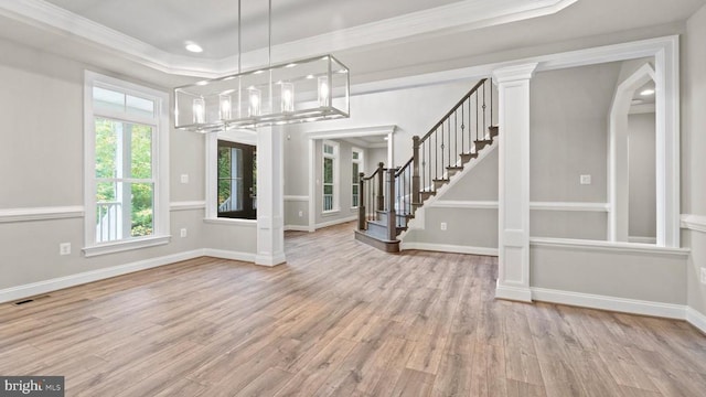 interior space featuring a notable chandelier, crown molding, light hardwood / wood-style flooring, and decorative columns