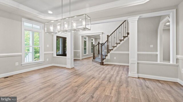 interior space featuring a notable chandelier, crown molding, light hardwood / wood-style flooring, and decorative columns