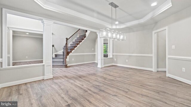 interior space with ornamental molding, a tray ceiling, and light hardwood / wood-style floors