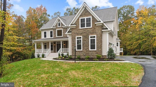 craftsman inspired home featuring a garage, a front yard, and a porch